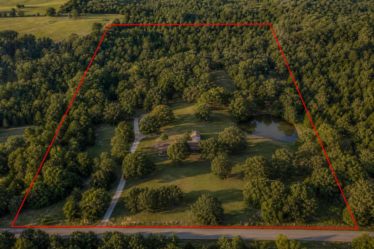 Aerial photograph of a wooded acreage parcel with estimated property lot lines drawn in red