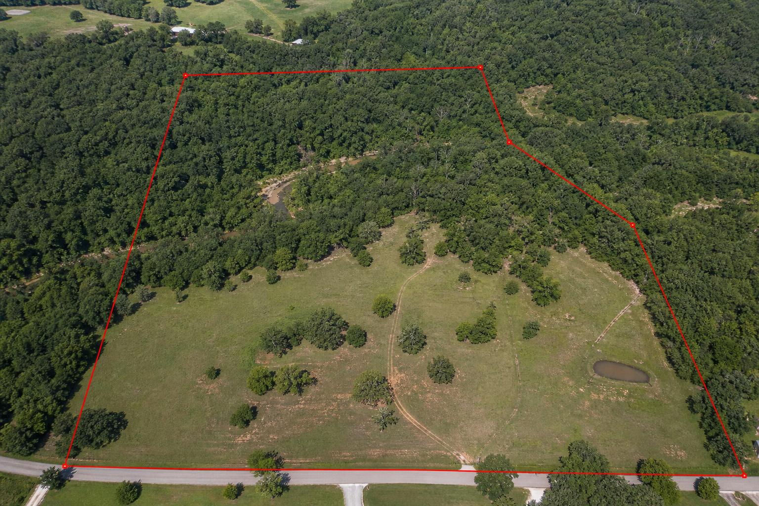 Aerial view of a pasture and forest mix with red estimated property boundary lines