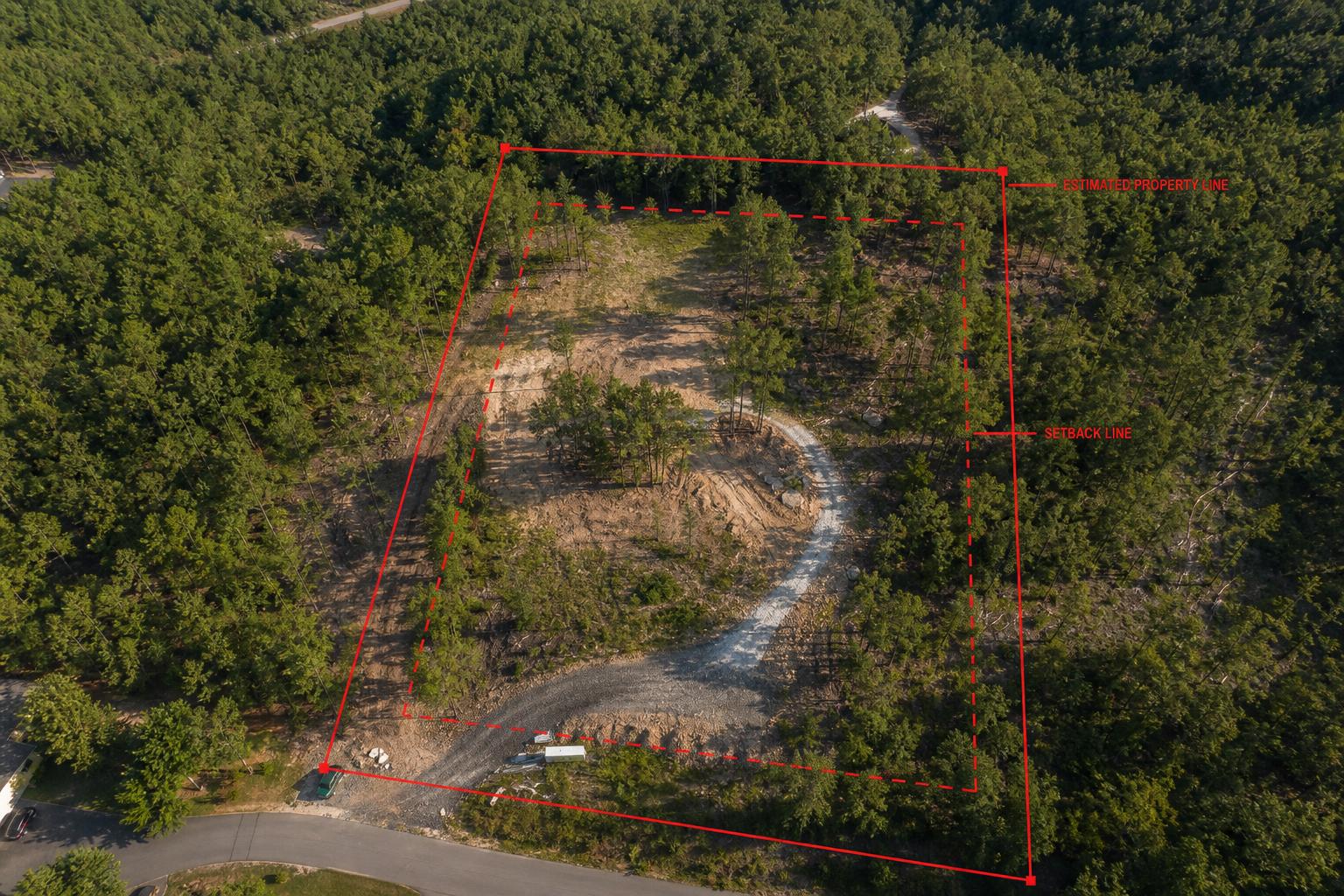Aerial view of a hillside building lot with red estimated property boundary and setback lines